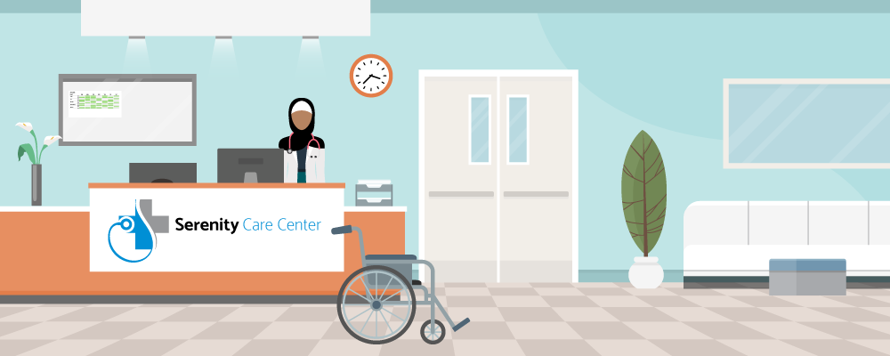 Zareen stands behind the nurses’ station, which has computer and files on it. A wheelchair, plants, and furniture are nearby.