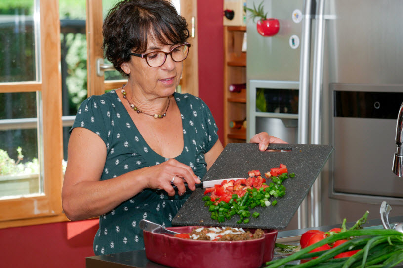 Smiling middle-aged brunette woman preparing meal