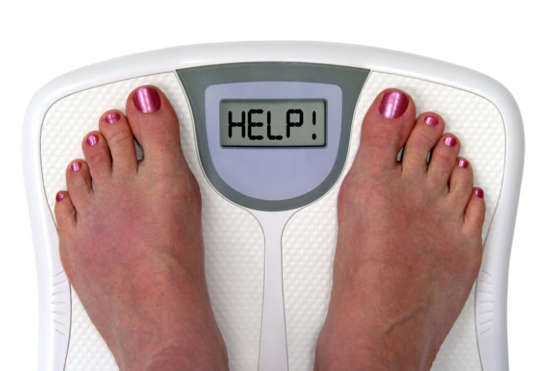 Feet on a bathroom scale with the word help! on the screen.
